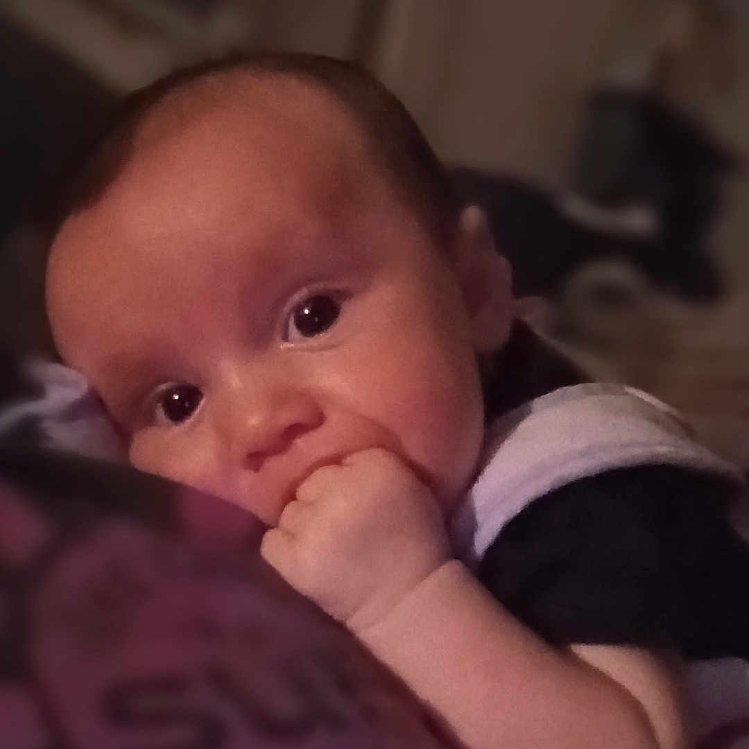 Addison is registered to the contest to win money with this photo: arm, baby, bodypart, clothing, face, finger, frown, hand, happy, head, indoors, mouth, newborn, person, photography, portrait, sitting, smile, t_shirt, wrist