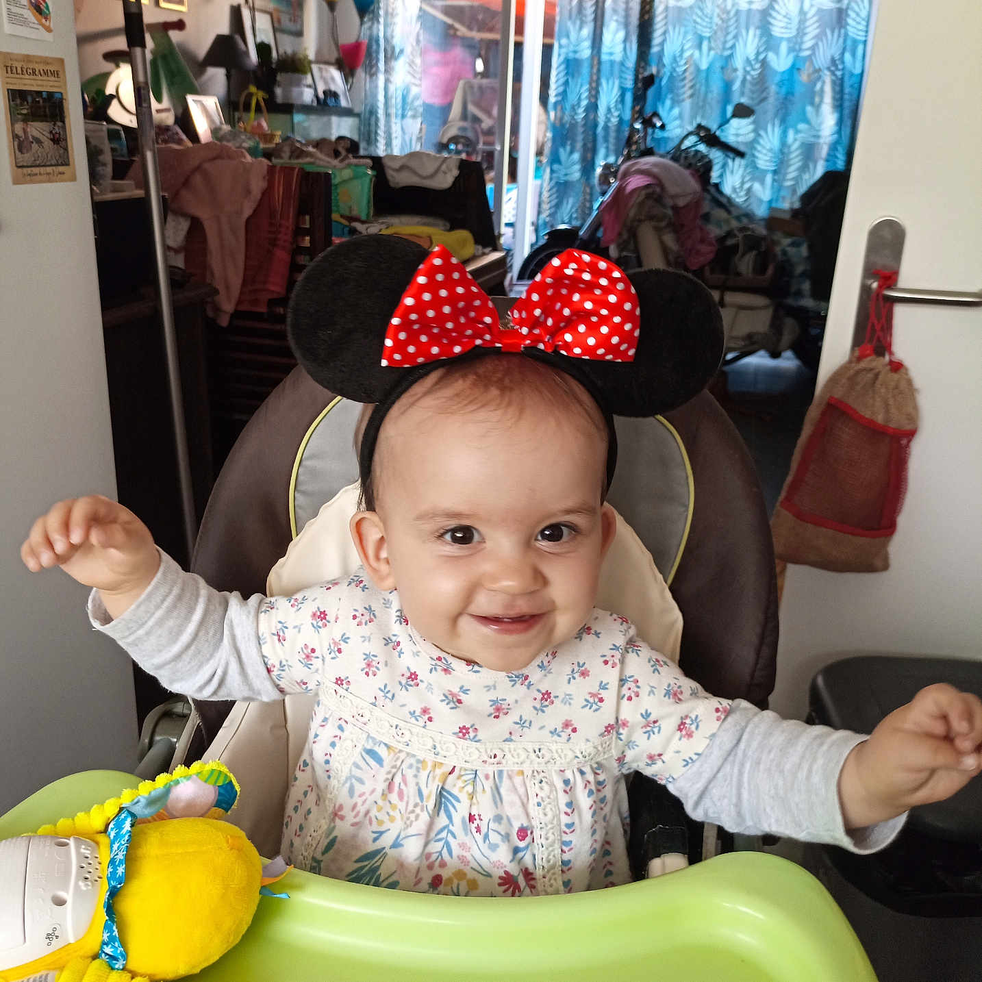 Lyana a rejoint le concours — aidez-le/la à gagner de superbes lots ! arms_outstretched, baby, child, clothing, curtains, ears, furniture, happy, headband, high_chair, indoor, light, living_room, minnie_mouse, person, polka_dot, red_bow, smile, toy, window