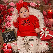 Raelynn is registered to the contest to win money with this photo: baby, bow, candles, chalkboard, child, confetti, flowers, headband, heart_balloon, heart_box, hearts, infant, pacifier, plush_blanket, portrait, red_clothing, roses, sitting, valentine, wooden_bed