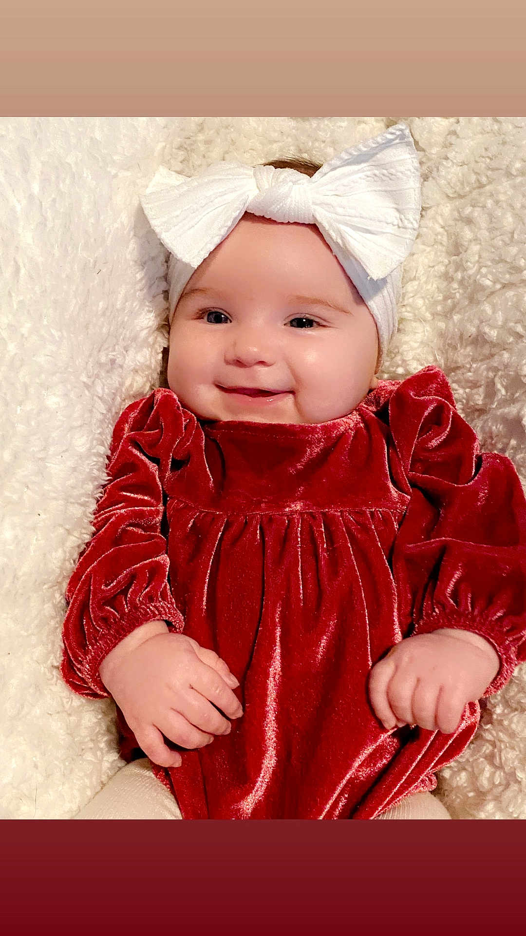 Raelynn is registered to the contest to win money with this photo: baby, infant, headband, white_bow, red_velvet_dress, velvet, blanket, fluffy, smile, cheeks, hands, portrait, lying_down, cozy, soft_texture, cute, festive_outfit, holiday, eyes, skin