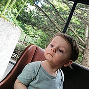 Julian a rejoint le concours — aidez-le/la à gagner de superbes lots ! toddler, child, portrait, outdoor, greenery, trees, bamboo, seat, leather, curious, casual_clothing, short_sleeves, nature, daylight, young_child, person, looking_away, relaxed, background, park