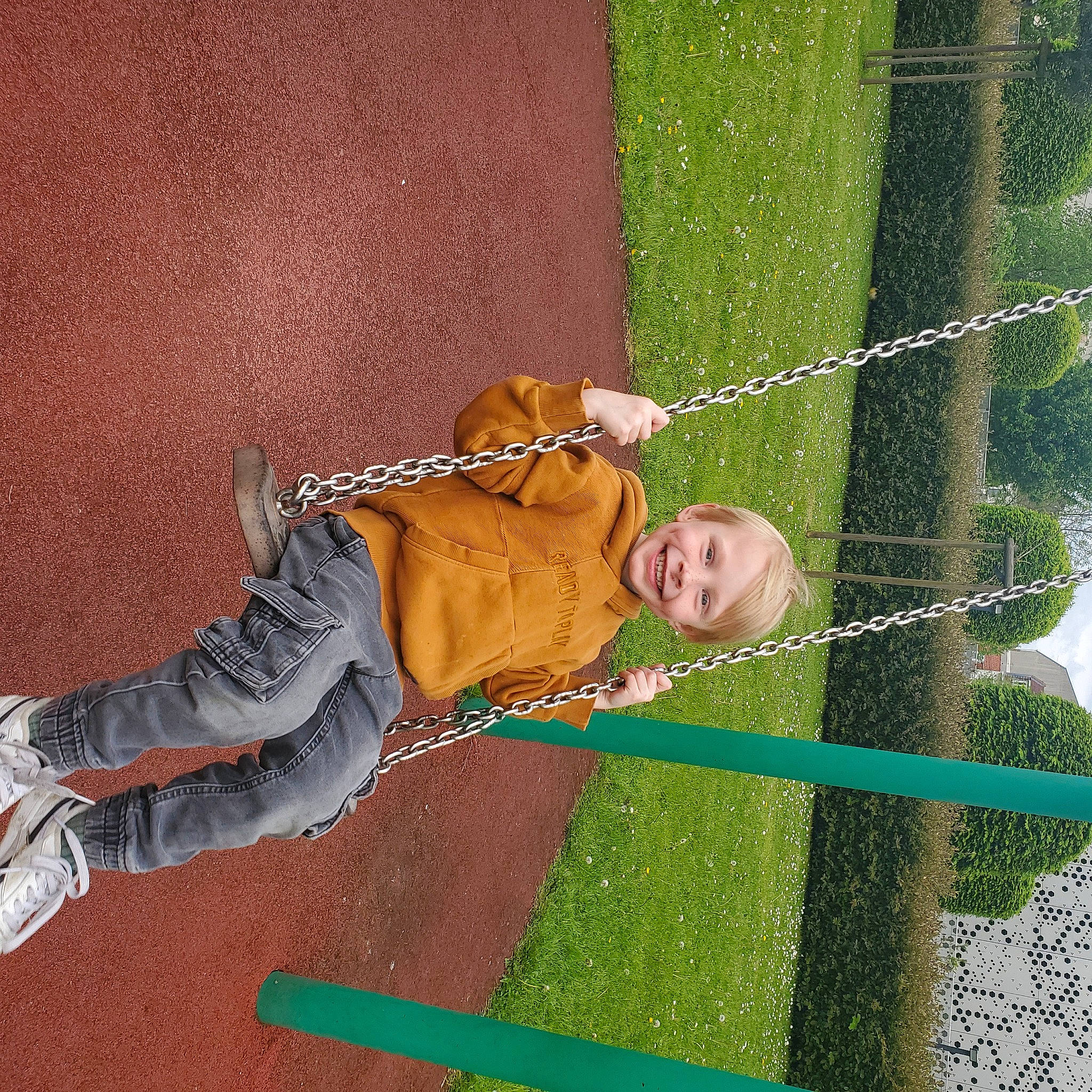 Inenzo participe au concours pour gagner de l'argent avec cette photo : child, flooring, fun, grass, happy, joy, leisure, outdoor_play_equipment, pattern, people_in_nature, person, play, playground, recreation, shadow, sitting, smile, swing, toddler, wood