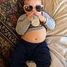 Clyde is registered to the contest to win money with this photo: toddler, child, sunglasses, bottle, couch, blanket, indoor, clothing, pants, shirt, barefoot, face, relaxing, baby, drinking, furniture, pattern, home, casual, cute