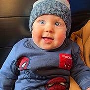 Clyde joined the competition — help win amazing prizes! baby, child, blue_eyes, knitted_hat, red_pom_pom, spiderman_outfit, sweater, pants, smiling, cute, indoor, seated, blanket, mustard_color, soft_lighting, face, headwear, winter_clothing, portrait, infant