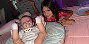 Shine is registered to the contest to win money with this photo: baby, child, smiling, pacifier, pillow, bedroom, snacks, plate, blanket, curtains, furniture, bracelet, pink, white, person, indoor, happy, toddler, infant, cushion