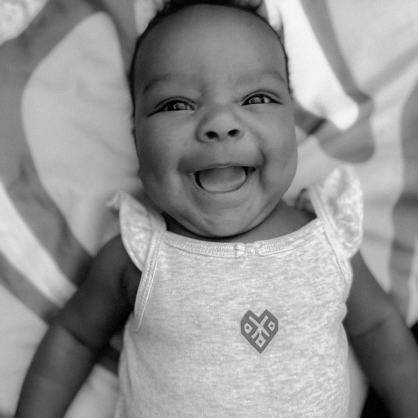 Amiah is registered to the contest to win money with this photo: baby, black_and_white, child, clothing, cute, eyes, face, happy, head, infant, joyful, lying_down, mouth, patterned_blanket, person, portrait, skin, sleeveless_top, small_child, smiling