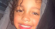 Zai'Lynn is registered to the contest to win money with this photo: baby, blanket, blanket_wrap, cheerful, child, closeup, cozy, curly_hair, cute, dark_background, face, happy, headshot, indoors, person, portrait, skin, smiling, warm_lighting, young