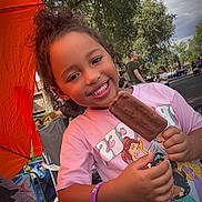 Zai'Lynn joined the competition — help win amazing prizes! child, smiling, outdoor, portrait, ice_pop, chocolate, dessert, pink_shirt, cartoon_shirt, curly_hair, bracelet, summer, festival, event, orange_canopy, trees, crowd, chair, happy, food