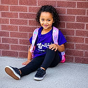 Zai'Lynn joined the competition — help win amazing prizes! child, sitting, brick_wall, purple_shirt, pink_backpack, curly_hair, smile, black_shoes, black_leggings, outdoor, concrete_floor, casual_clothing, young_girl, portrait, daylight, happy, resting, fashion, person, cute