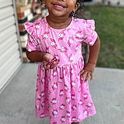 Zai'Lynn joined the competition — help win amazing prizes! child, girl, smiling, pink_dress, unicorn_pattern, holding_candy, standing, porch, concrete, outdoor, house, footwear, crocs, earrings, curly_hair, happy, portrait, casual_clothing, daylight, background_blur