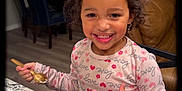 Zai'Lynn is registered to the contest to win money with this photo: balloons, child, clothing, curly_hair, decorations, earrings, eating, face, happy, holiday, home, indoor, jewelry, kitchen, long_sleeve, person, plate, smiling, spoon, table