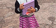Zai'Lynn joined the competition — help win amazing prizes! black_jacket, black_shoes, casual_clothing, child, curly_hair, cute, daylight, girl, gravel, happy, outdoor, person, portrait, purple_tablet_case, smiling, standing, striped_skirt, tablet, white_socks, young