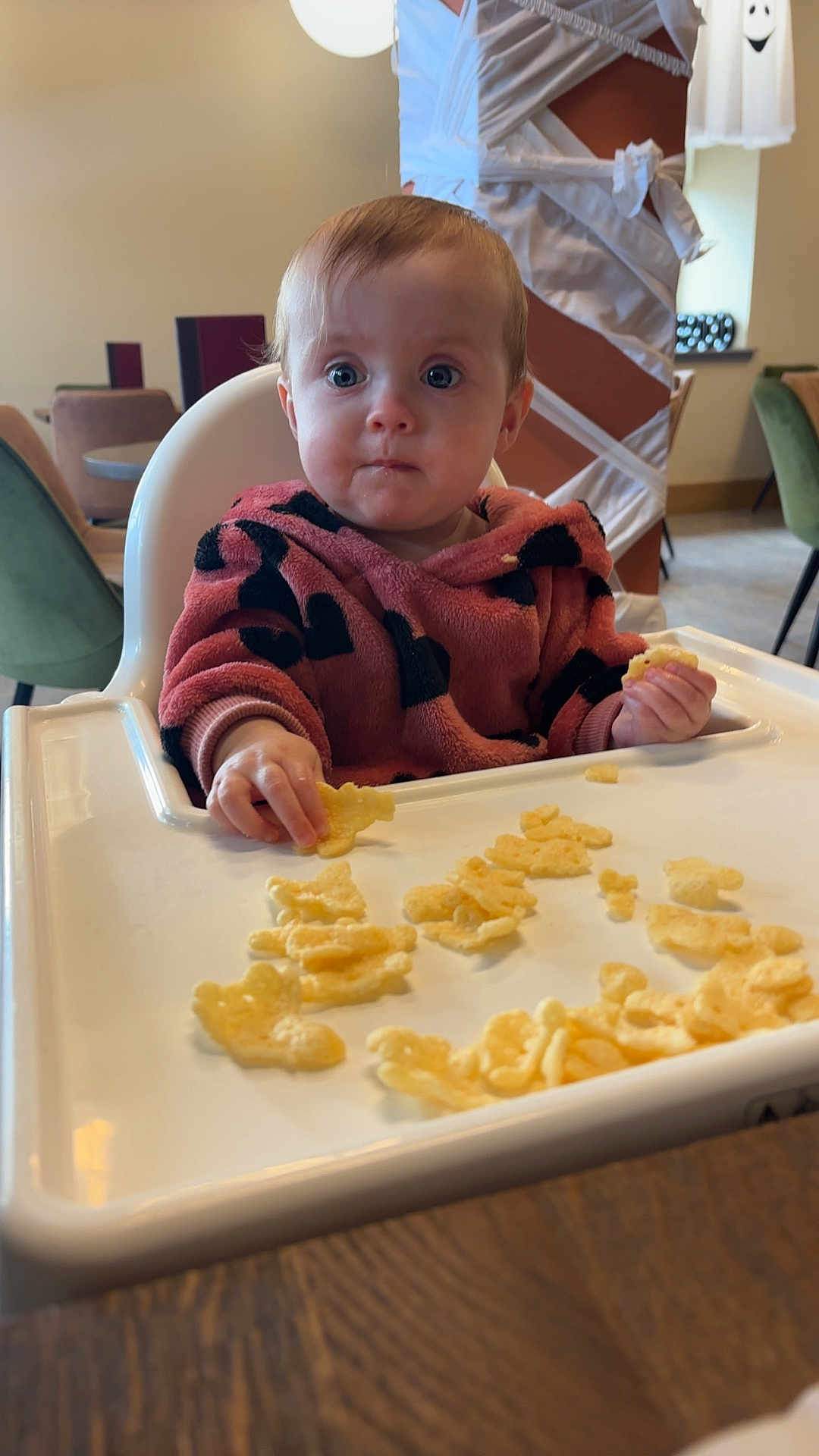Isabella is registered to the contest to win money with this photo: baby, high_chair, snack, indoor, child, food, table, furniture, person, cute, expression, cozy, modern, casual, seat, plate, eating, young_child, curious, comfortable