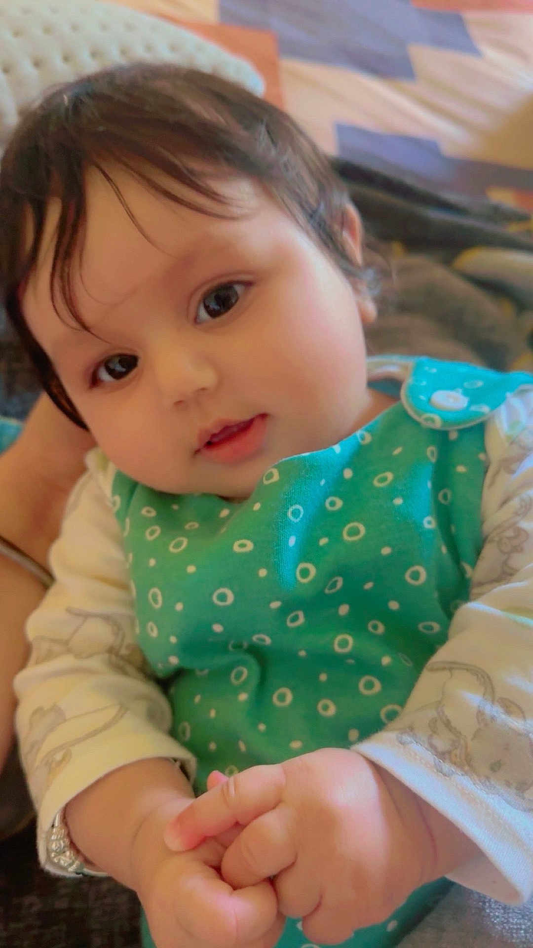 Arzoi is registered to the contest to win money with this photo: baby, child, infant, face, hands, clothing, green_outfit, polka_dots, cute, portrait, indoors, closeup, young_child, skin, person, head, eyes, expression, sitting, soft_light