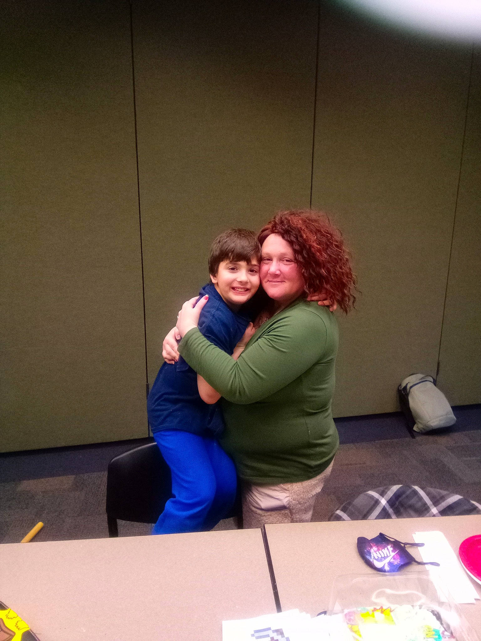 Nick is registered to the contest to win money with this photo: bag, chair, child, conversation, event, flooring, fun, happy, job, joy, leisure, luggage_and_bags, person, plate, recreation, room, sitting, smile, t_shirt, table