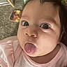 baby, infant, child, portrait, close_up, face, wide_eyes, tongue, sticking_out_tongue, pink_clothing, onesie, sitting, lying_down, indoor, blanket, toy, carpet, home, adorable, funny_expression