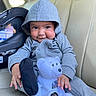 baby, beige_seat, car_interior, car_seat, child, clothing, cozy, cute, face, hand, hoodie, indoor, infant, plush, portrait, sitting, smile, teddy_bear, toy, young_child