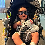 Kendrick joined the competition — help win amazing prizes! baby, baby_clothes, car_seat, child, clothing, footwear, furniture, happy, headwear, indoor, person, room, seatbelt, smiling, sock, stroller, stuffed_bear, sunglasses, toy, window
