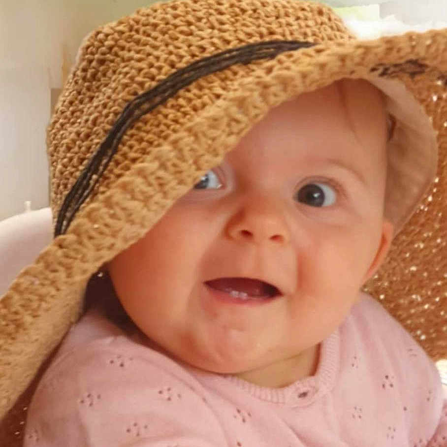 Lila participe au concours pour gagner de l'argent avec cette photo : baby, background_blur, child, closeup, cute, eyewear_cover, face, happy, hat, headwear, indoors, infant, person, pink_clothing, portrait, sitting, smiling, soft_light, woven_hat, young_child