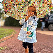 Octavie a rejoint le concours — aidez-le/la à gagner de superbes lots ! child, girl, umbrella, raincoat, mickey_mouse, outdoor, smiling, walking, rain, footwear, pathway, toy, person, cartoon, colorful, jacket, happy, cute, fashion, weather