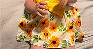 Emery joined the competition — help win amazing prizes! baby, child, smiling, yellow_dress, sunflower_pattern, infant, hands, legs, bed, blanket, happy, cute, person, portrait, indoor, clothing, skin, feet, comfort, playful