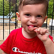 Soan participe au concours pour gagner de l'argent avec cette photo : toddler, child, red_shirt, lollipop, smiling, outdoor, deck, wooden_floor, garden, patio_furniture, boy, short_hair, daylight, happy, cute, person, portrait, summer, playful, casual_clothing