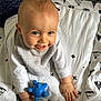 Tom participe au concours pour gagner de l'argent avec cette photo : baby, bed, bedroom, blanket, bodypart, crawling, face, finger, furniture, hand, happy, head, helmet, person, photography, portrait, quilt, sitting, smile, toy