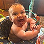 baby, child, smiling, happy, messy, chocolate, face, arms, highchair, baby_seat, indoor, colorful, pattern, feathers, toy, person, cute, infant, playful, expression