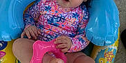 Amelia is registered to the contest to win money with this photo: baby, big_eyes, child, colorful, concrete, curly_hair, footwear, infant, inflatable_pool_seat, outdoor, person, pink_inflatable_ring, playful, sitting, summer, sunlight, swimsuit, toy, water_toy, yellow_inflatable_ring