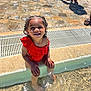 toddler, child, swimsuit, red_clothing, water, pool, sitting, sunlight, outdoor, stone_pavement, feet, smiling, happy, summer, sunny, person, playing, vacation, reflection, shallow_water