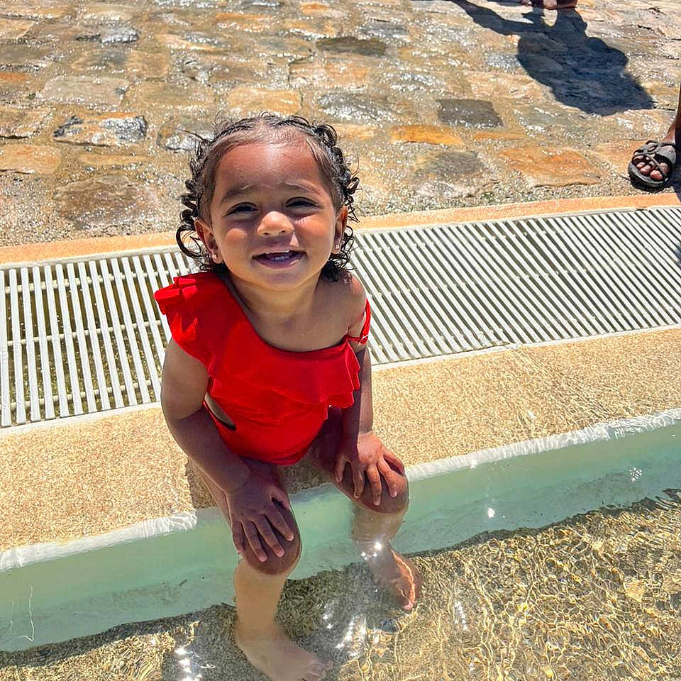 Shaelys participe au concours pour gagner de l'argent avec cette photo : child, feet, happy, outdoor, person, playing, pool, red_clothing, reflection, shallow_water, sitting, smiling, stone_pavement, summer, sunlight, sunny, swimsuit, toddler, vacation, water