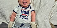 Kristopher Atlass joined the competition — help win amazing prizes! baby, infant, smiling, tongue_out, clothing, mittens, blanket, bed, cute, happy, person, child, apparel, socks, lying_down, indoor, portrait, young_child, text_on_clothing, fabric