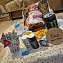 baby, infant, food, plate, mac_and_cheese, ribs, drink_can, monster_energy, bottle, milestone_sign, tablecloth, living_room, couch, pillow, face, smudged_food, baby_seat, blanket, decor, person