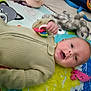 baby, child, toy, stuffed_animal, play_mat, colorful, indoor, infant, happy, smiling, clothing, hand, face, floor, candid, young, blurred, cute, childhood, playtime