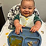 Cooper joined the competition — help win amazing prizes! baby, high_chair, messy, food, plate, bib, hands, face, smile, feeding, meal, child, indoor, star_pattern, clothing, table, white, orange_food, green_clothing, happy
