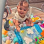 Cooper is registered to the contest to win money with this photo: baby, smiling, playpen, toys, plastic_balls, inflatable_toy, soft_toys, child, indoor, colorful, happy, sitting, cute, infant, play, mesh_netting, floor, clothing, person, bright