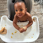 Daxon Dodds joined the competition — help win amazing prizes! toddler, child, high_chair, bread, crumbs, carpet, food, snack, messy, indoor, person, cute, hair_buns, looking_up, hands, tray, feeding_time, baby, skin, expression