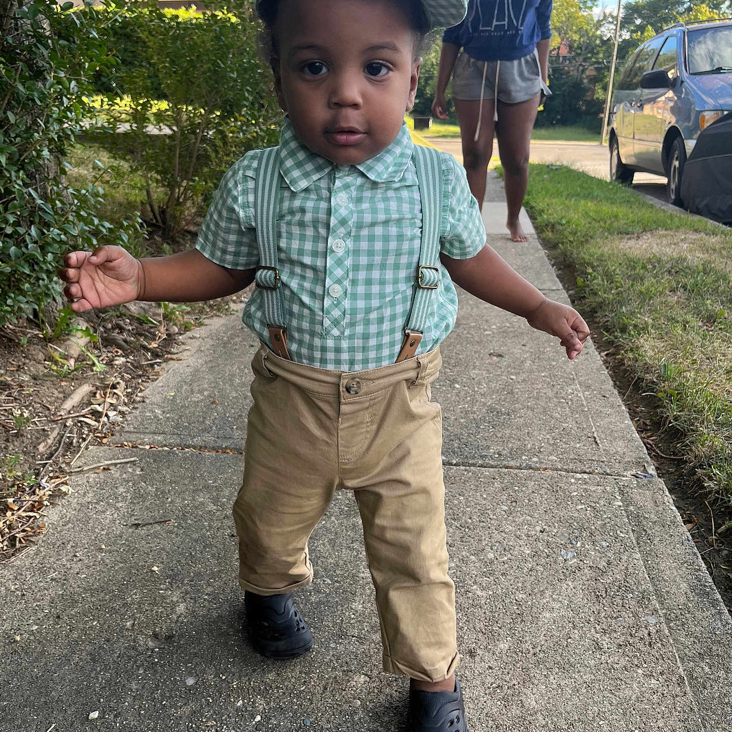 Daxon Dodds joined the competition — help win amazing prizes! barefoot, black_shoes, bushes, car, casual_clothing, child, daylight, grass, green_checkered_cap, khaki_pants, outdoor, person, residential_area, sidewalk, suburban, summer, suspenders, toddler, walking, young_woman
