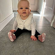 Hillarya a rejoint le concours — aidez-le/la à gagner de superbes lots ! baby, child, floor, tile, vest, booties, pink, white, blue_eyes, smile, sitting, indoor, hands, toes, curious, person, crawling, young_child, casual_clothing, hallway
