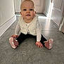 baby, child, floor, tile, vest, booties, pink, white, blue_eyes, smile, sitting, indoor, hands, toes, curious, person, crawling, young_child, casual_clothing, hallway