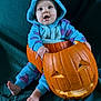 Hillarya a rejoint le concours — aidez-le/la à gagner de superbes lots ! baby, child, pumpkin, halloween, costume, onesie, blue, purple, carved_pumpkin, face, smiling, cute, sitting, barefoot, indoors, portrait, holiday, festive, dark_background, fabric