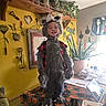 child, costume, curtain, decor, drink_can, face, halloween, indoor, kitchen, phone, plant, plate, potted_plant, pumpkin_pattern, smile, table, toy, window, wolf, yellow_wall