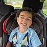 Ryder is registered to the contest to win money with this photo: blue_shirt, car_interior, car_seat, casual_clothing, child, curly_hair, cute, expression, fun, happy, portrait, rain, safety, seat_headrest, seatbelt, smiling, toddler, vehicle, window, young_child