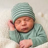Samuel is registered to the contest to win money with this photo: newborn, baby, sleeping, hat, striped_hat, green_clothing, knit_blanket, cozy, infant, peaceful, resting, closeup, portrait, soft_texture, cute, child, baby_hand, baby_face, indoors, warm