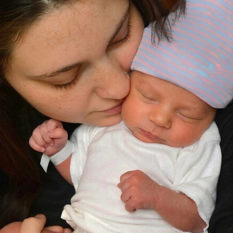 Samuel is registered to the contest to win money with this photo: baby, newborn, infant, mother, woman, face, sleeping, hat, striped_hat, white_clothing, skin, closeup, affection, love, family, holding, peaceful, portrait, indoor, tender