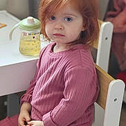 Piper is registered to the contest to win money with this photo: blue_eyes, casual_clothing, child, cozy, curtain, face, furniture, home, indoor, natural_light, person, pink_outfit, portrait, red_hair, sippy_cup, sitting, table, thoughtful, wooden_chair, young_child