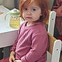 blue_eyes, casual_clothing, child, cozy, curtain, face, furniture, home, indoor, natural_light, person, pink_outfit, portrait, red_hair, sippy_cup, sitting, table, thoughtful, wooden_chair, young_child