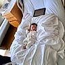 newborn, baby, infant, child, hospital, hospital_bed, blanket, white_sheets, sleeping, face, eyes_closed, portrait, onesie, clothing, letter_blocks, tablet, smartphone, bedside_table, indoor, medical_room