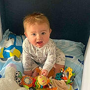 Nino participe au concours pour gagner de l'argent avec cette photo : baby, child, toy, plush, bed, onesie, colorful, smiling, happy, indoor, cute, infant, rattle, playful, person, young, childhood, soft, fun, animal_print