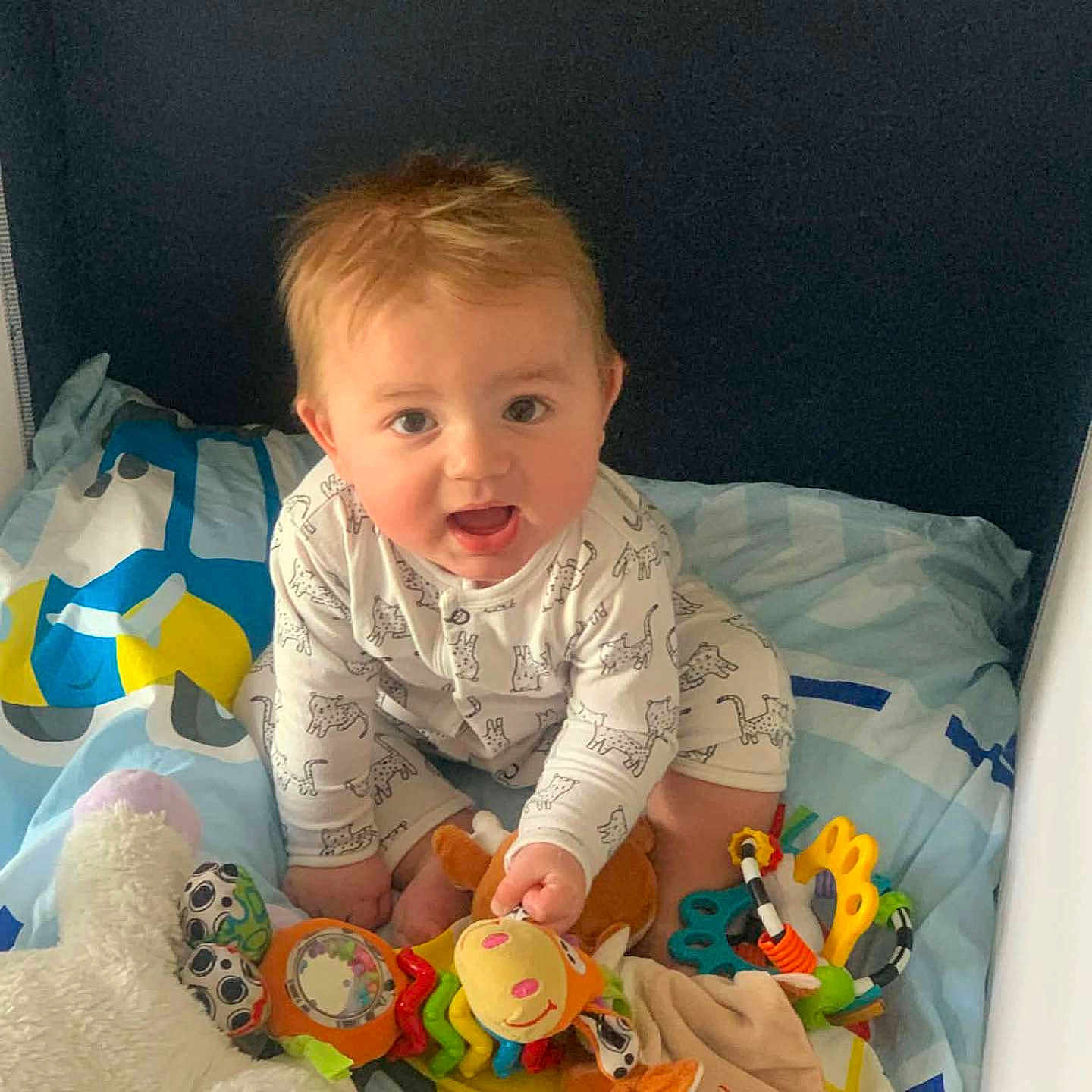Nino participe au concours pour gagner de l'argent avec cette photo : baby, child, toy, plush, bed, onesie, colorful, smiling, happy, indoor, cute, infant, rattle, playful, person, young, childhood, soft, fun, animal_print